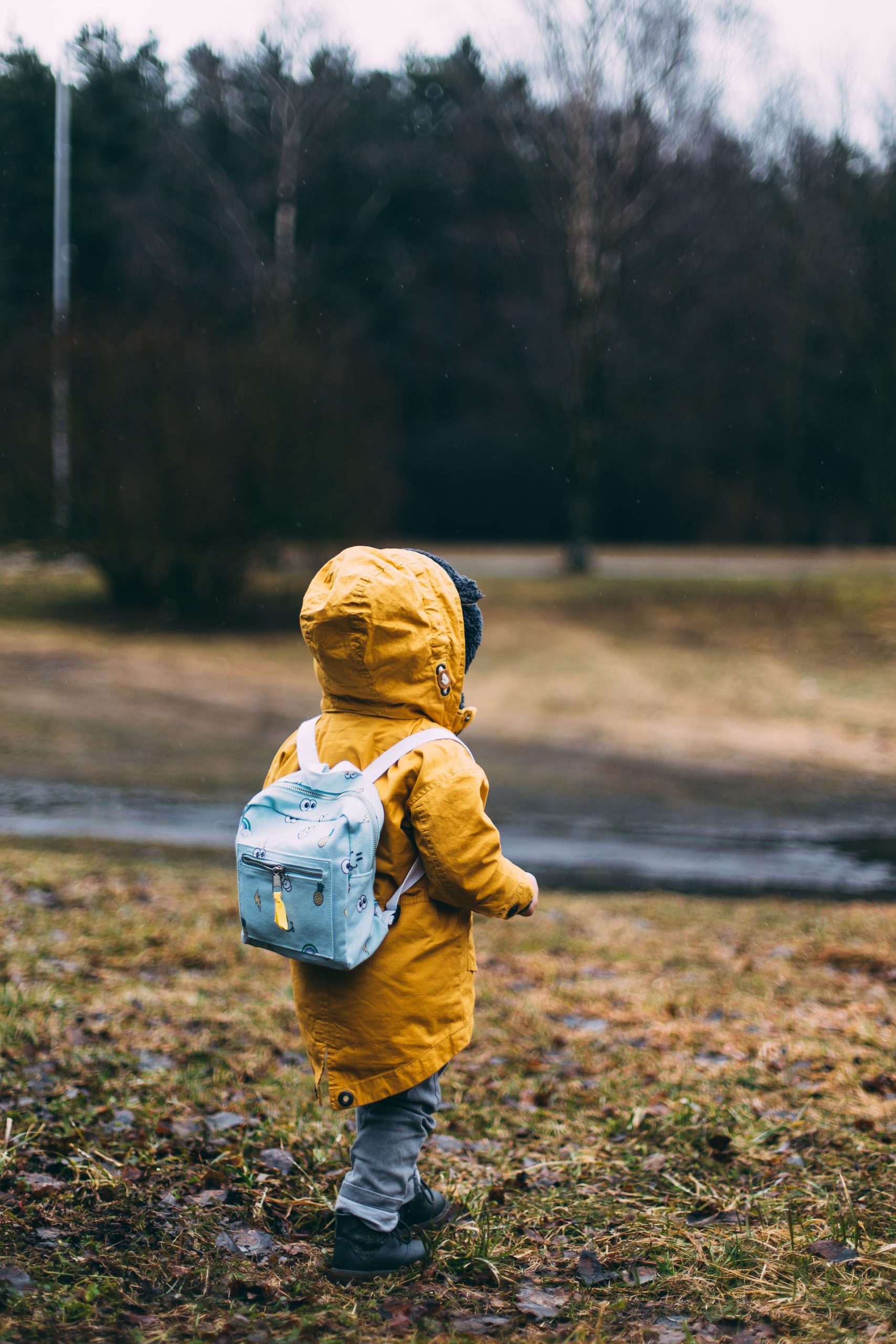 Child walking to school with backpack and jacket on.