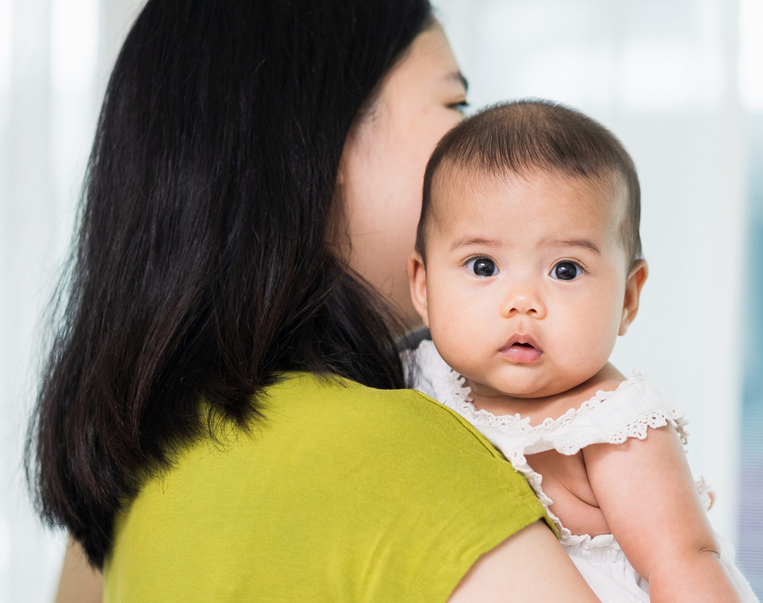 Mother holding a child over her shoulder.